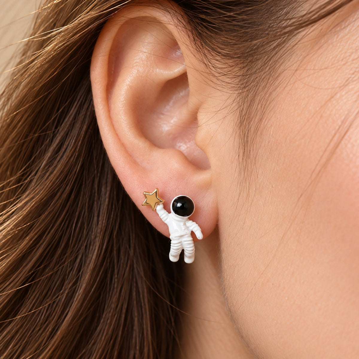 Model wearing astronaut and gold star stud earring, cute space jewelry