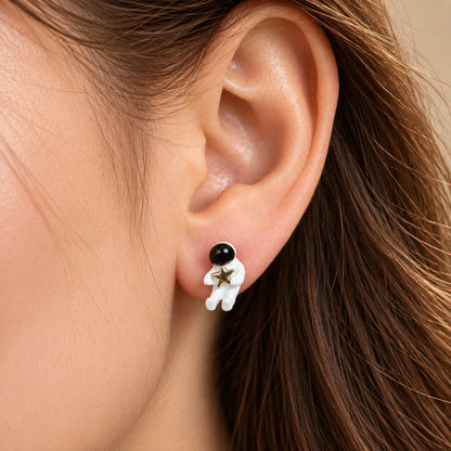 Close up of white astronaut stud earring holding a gold star on the ear