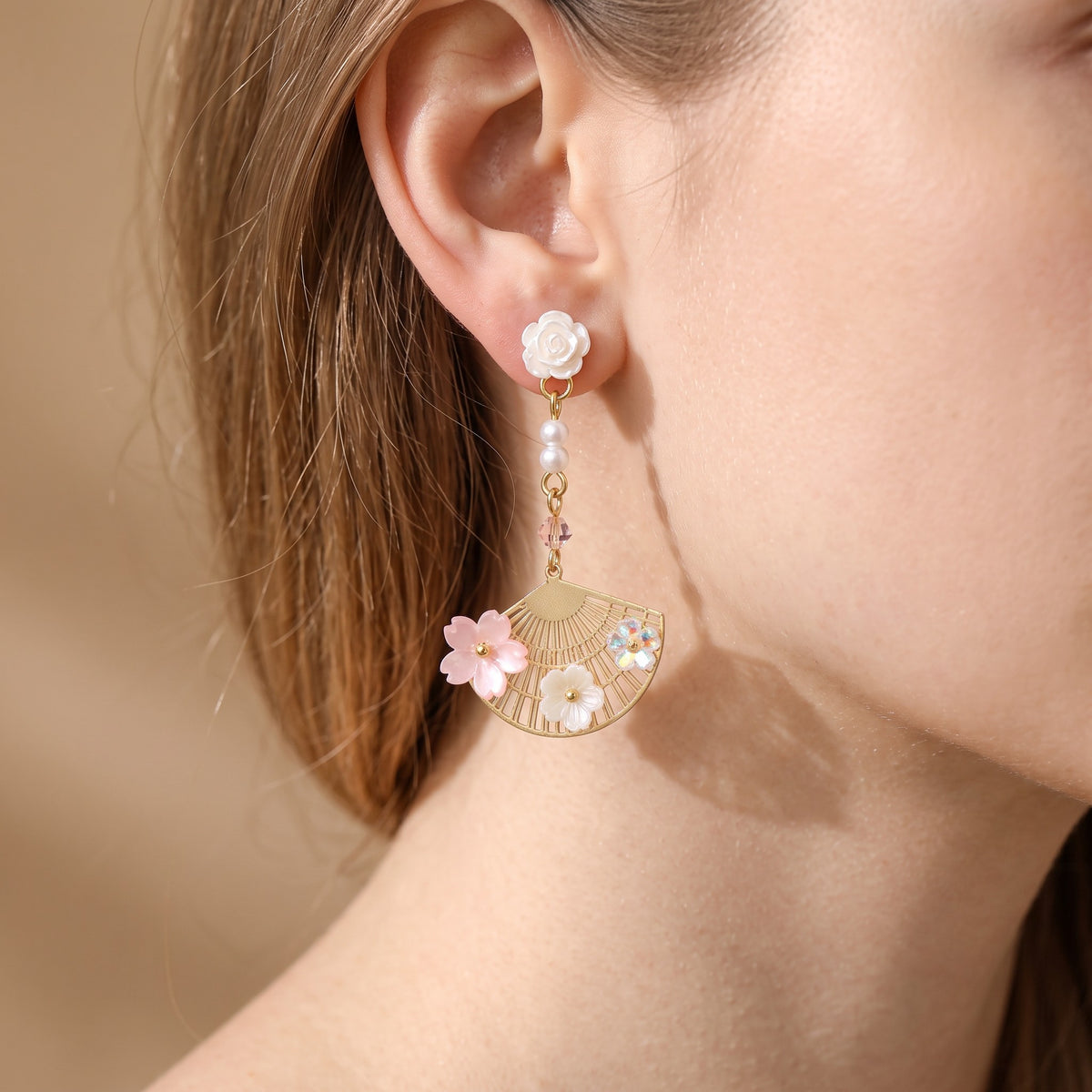 Woman wearing gold fan earring with pink sakura flowers