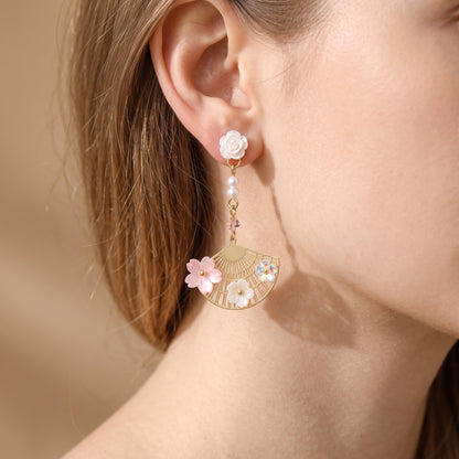 Woman wearing gold fan earring with pink sakura flowers