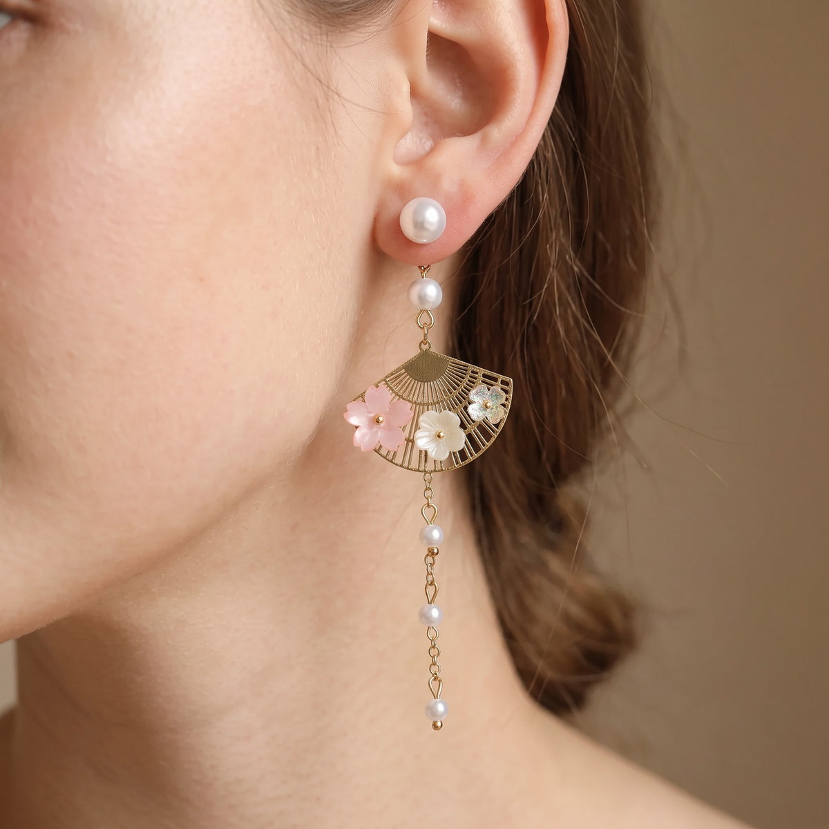 Close-up of pearl stud with cherry blossom fan drop on ear