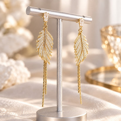 Gold leaf drop earrings with pavé crystal feather and chain tassels on display stand