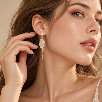 Woman wearing gold leaf feather tassel drop earrings