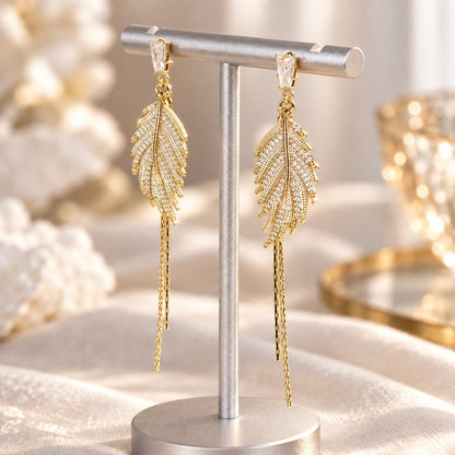 Gold feather tassel dangle earrings on jewelry stand
