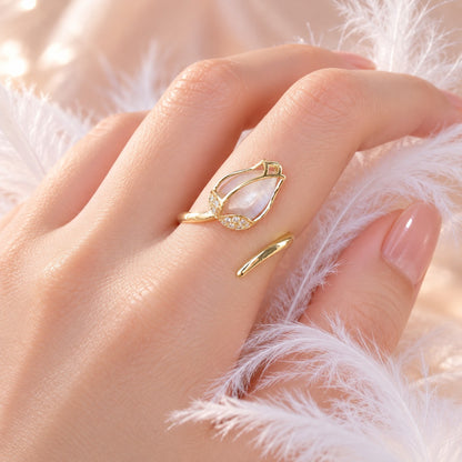 Hand wearing dainty gold tulip wrap ring among feathers
