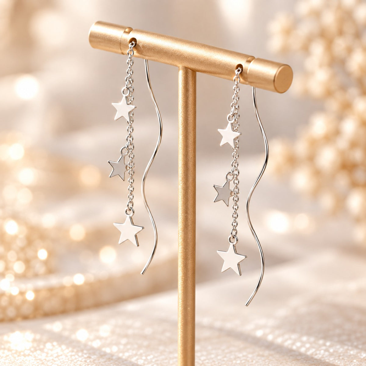 Silver star threader earrings with wavy bar on gold display stand