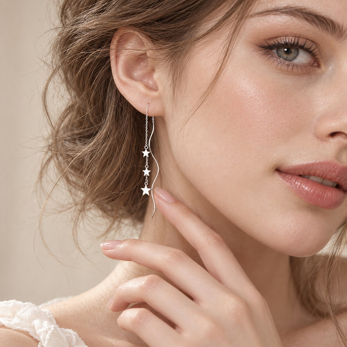 Woman wearing dainty silver star threader earrings