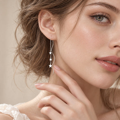 Woman wearing dainty silver star threader earrings