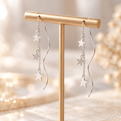 Silver star chain drop earrings hanging on jewelry stand