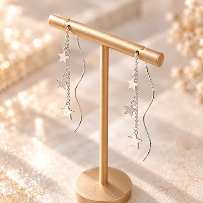 Dainty silver star and wave bar threader earrings on display
